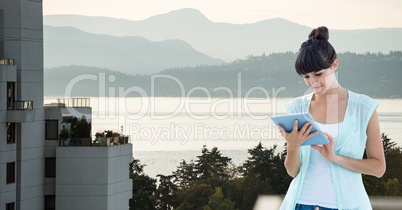 Beautiful woman looking at digital tablet while standing on building against mountains