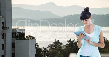 Beautiful woman looking at digital tablet while standing on building against mountains