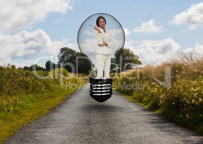 Businesswoman standing in bulb over road against sky