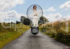 Businesswoman standing in bulb over road against sky
