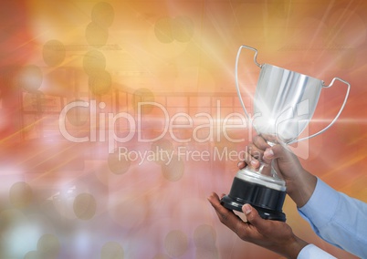 Business hand with trophy against a gold background and flares