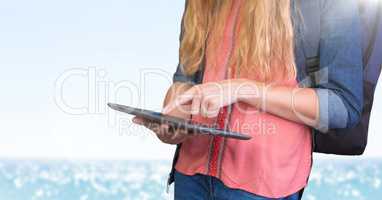 Woman mid section with backpack and tablet against blurry water and flare