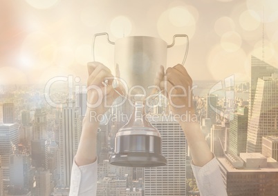 business hand with trophy in front of the city with gold lights