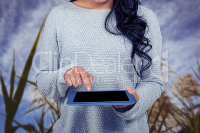 Mid section of woman using digital tablet against field