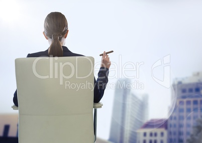 Back of seated business woman smoking cigar against blurry buildings and flare