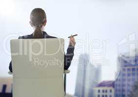 Back of seated business woman smoking cigar against blurry buildings and flare