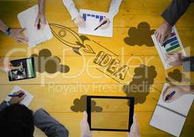 Overhead of business team with yellow wood panel and rocket doodle