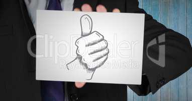 Business man mid section with card showing thumbs up doodle against blue wood panel