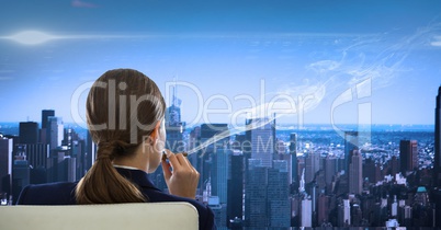 Rear view of businesswoman sitting in chair smoking looking at cityscape