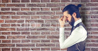 Side view of tensed businessman standing by brick wall