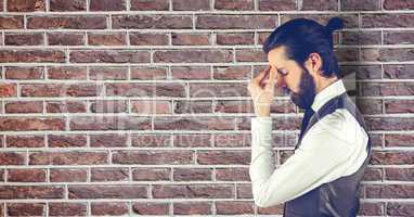 Side view of tensed businessman standing by brick wall