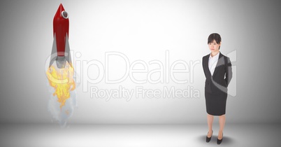 Digital composite image of businesswoman standing by rocket launch against gray background