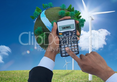 Digital composite image of hands using calculator with planet earth and windmills on grassy field ag
