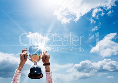 Business hands with trophy in front of a blue sky