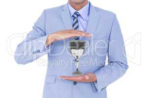 Business man holding a trophy in his hands against white background
