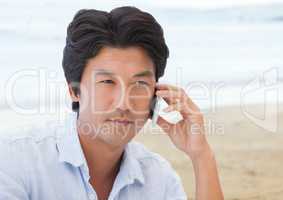 Man on phone against blurry beach