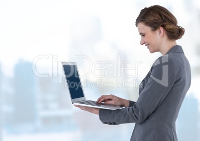 Businesswoman holding laptop in bright blue motion public space