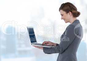 Businesswoman holding laptop in bright blue motion public space