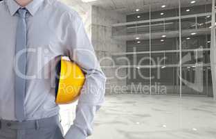 architect holding yellow safety helmet against room background