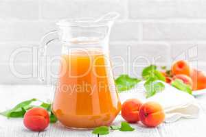 Apricot juice and fresh fruits with leaves on white wooden table