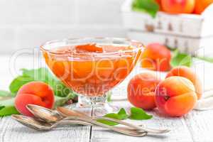 Apricot jam and fresh fruits with leaves on white wooden table