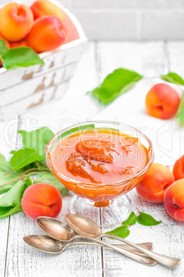 Apricot jam and fresh fruits with leaves on white wooden table