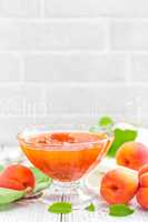 Apricot jam and fresh fruits with leaves on white wooden table