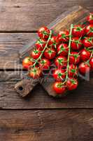 Fresh cherry tomatoes on twigs on wooden table, top view