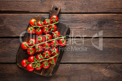 Fresh cherry tomatoes on twigs on wooden table, top view