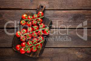 Fresh cherry tomatoes on twigs on wooden table, top view