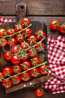 Fresh cherry tomatoes on twigs on wooden table, top view