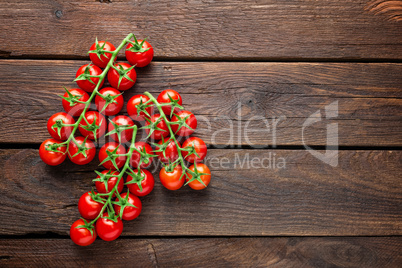 Fresh cherry tomatoes on twigs on wooden table, top view