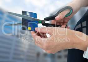 Hands cutting bank card with buildings