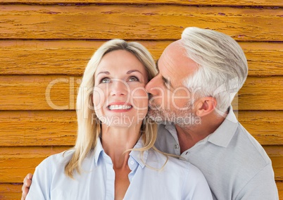 couple: man giving kiss to the woman with yellow wood background