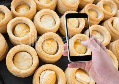 Hand of person taking a picture of cakes with her smartphone