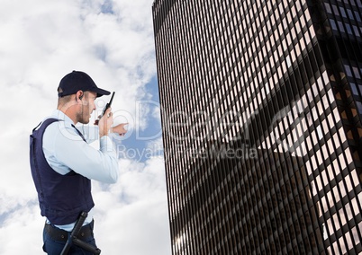 Security guard talking on walkie talkie while pointing towards building