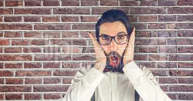 Creative businessman looking surprised while standing against brick wall