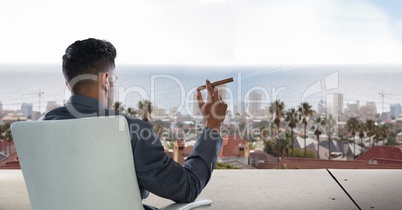Businessman sitting on chair and looking at city while smoking cigar