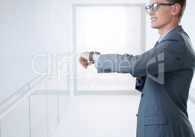 Businessman holding smart watch in bright corridor