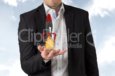 A business man is holding a rocket taking off on sky background