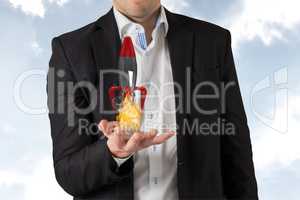 A business man is holding a rocket taking off on sky background