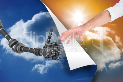 Human and robot touching their hands between blue sky and sunset