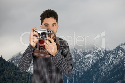 Casual man taking a photo in front of snow-covered mountains