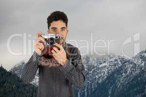 Casual man taking a photo in front of snow-covered mountains