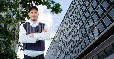 Portrait of confident security guard with arms crossed standing against building in city