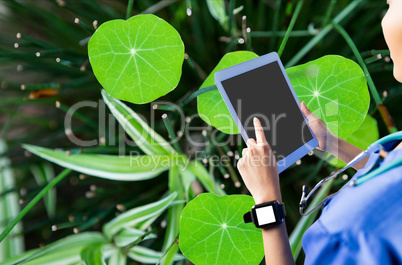 Woman using her tablet against leaves