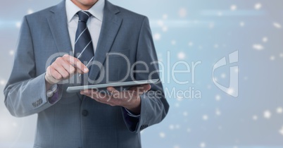 Businessman holding tablet with bright star spangled background