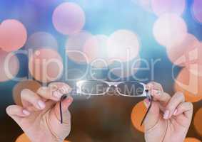 Hands holding shiny glasses with sparkling light bokeh background