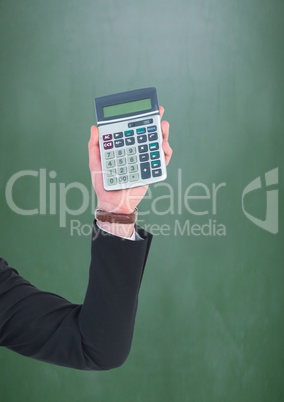Hand with calculator against green chalkboard