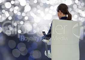 Businesswoman Back Sitting in Chair with  mobile phone and bokeh sparkling lights
